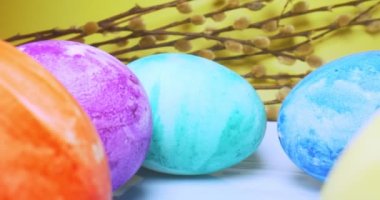 detailed extreme close-up, colorful easter eggs with pussy willow branches on yellow background