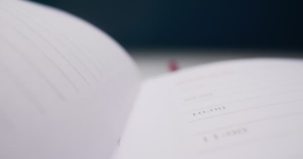 Detailed extreme close-up spread of a notebook with a red bookmark — Stock Video