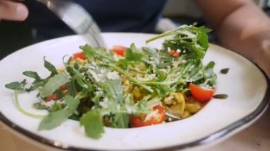 Yakın plan, birisi mantarlı ve mikro yeşillikli vegan arpa tabağıyla yemek yiyor.