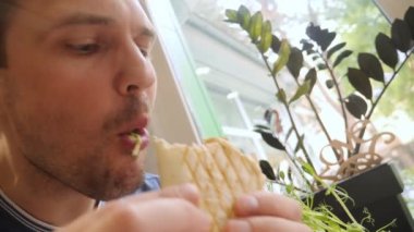 Kafede vejetaryen shawarma yiyen bir adamın yüzünü yakından çek.