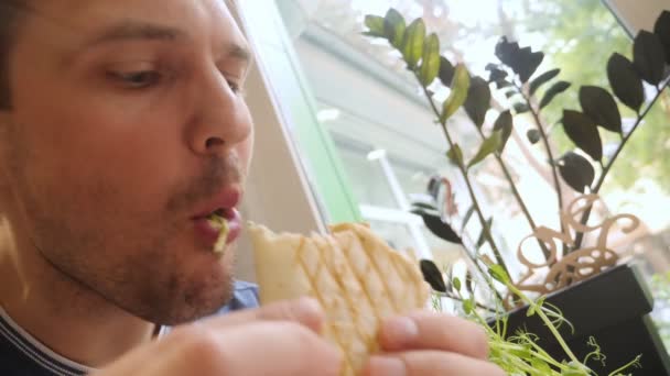 Közeli kép egy férfi arcát eszik vegán shawarma egy kávézóban — Stock videók