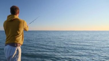 Denizde dönen bir çubukla balık tutan bir adam