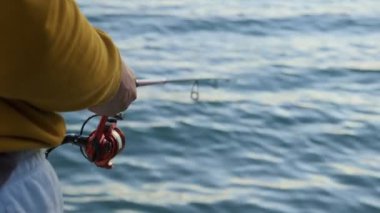 Denizde oltayla balık tutan bir adam, yakın plan.