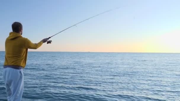Ένας άντρας που ψαρεύει με μια γυριστή ράβδο στη θάλασσα — Αρχείο Βίντεο