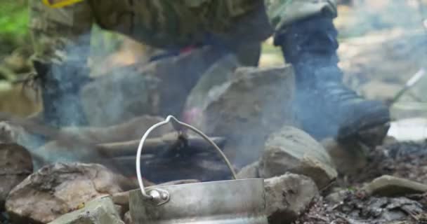 Nahaufnahme männlicher Beine in Stiefeletten am Feuer, das auf den Steinen gegrillt wird — Stockvideo