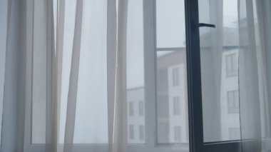 Yağmurlu bir günde penceredeki şeffaf perdeleri oynatmak
