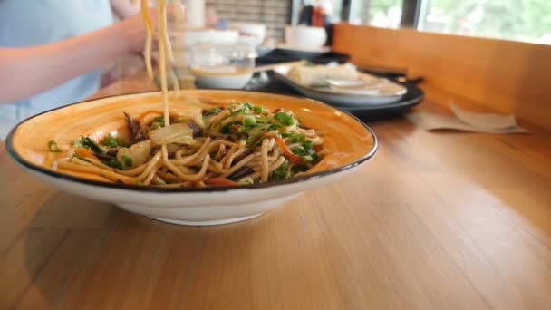 Крупный план блюд восточной кухни. люди едят азиатскую еду в кафе — стоковое видео