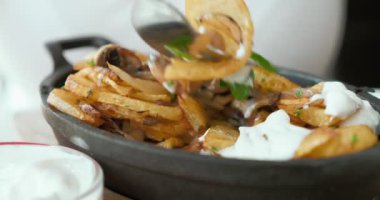 Yakın plan, birisi mantarlı kızarmış patates ve ekşi krema sosuyla yemek yiyor.