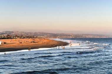 Pasifik Okyanusunda dalgalar ve günbatımında sahil manzarası, Newport Beach, California.