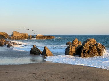 Gün batımında kayaların oluşumlarına çarpan dalgaların çarpıcı uzun süreli görüntüsü Sequit Point, Leo Carrillo State Beach, Malibu, California
