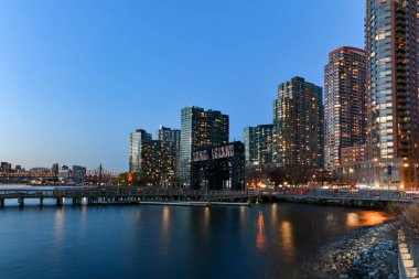 New York City - 7 Nisan 2021: Long Island City, Queens, New York 'tan gün batımında Manhattan şehir merkezi manzarası.