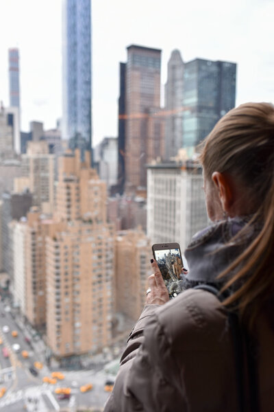 Girl photographing New York skyline with her smartphone.