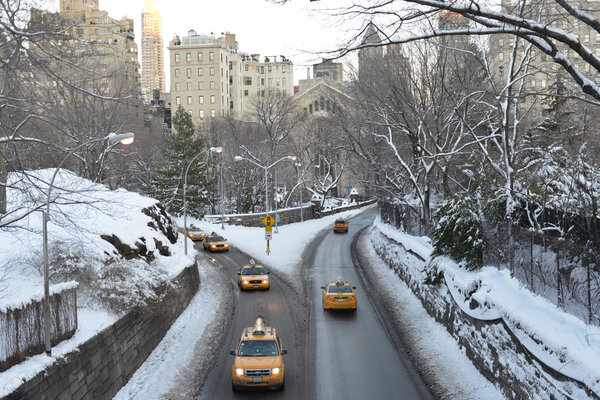 NEW YORK, NEW YORK - FEBRUARY 9, 2013: New York City taxi cabs driving through Central Park in the winter snow.