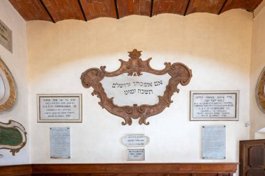 Pitigliano, İtalya - 13 Temmuz 2025: Pitigliano Sinagogu zarif avizeler ve kemerlere sahiptir. Minimalist duvarları ve kareli zemini resmi bir atmosfer yaratıyor.