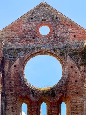 Chiusdino yakınlarındaki San Galgano 'daki 13. yüzyıl sarnıç manastırının Gotik tuğla naf kalıntıları büyük dairesel pencere açıklarını gösteriyor..