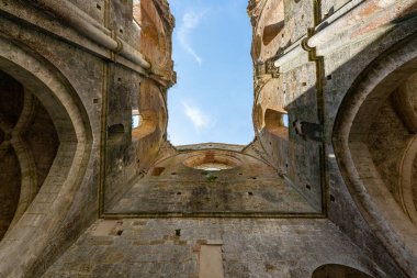 Çatısız Gotik Abbazia di San Galgano 'nun içinde, Chiusdino yakınlarındaki taş kasalar, kemerler ve yıpranmış duvarlar görünüyor..