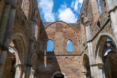 13. yüzyıl sarnıcı Abbazia di San Galgano 'nun iç kalıntıları, Chiusdino yakınlarında Gotik taş kemerler ve çatısız tuğla duvarlar gösteriyor..