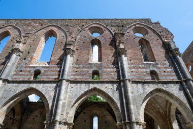 Chiusdino yakınlarındaki San Galgano Manastırı 'nın yıkık dökük duvarları ve tuğla naf duvarları açık yaz gökyüzü altında..