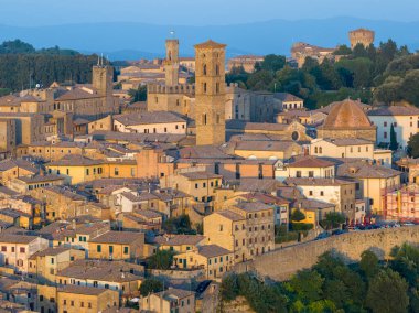 Ortaçağ Volterra 'sının günbatımındaki görüntüsü, taş evleri, savunma duvarlarını ve bu Etrüsk Tepesi kasabasının karakteristik kulelerini gösteriyor..