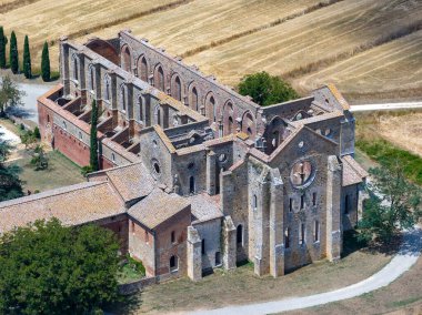 13. yüzyıl Gotik taş manastırı Chiusdino yakınlarındaki Toskana tarım arazisiyle çevrili çatısız kilisenin hava manzarası..