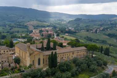 13. yüzyıl Chiesa di SantAgostino ve ortaçağ San Gimignano 'sunun Toskana tarım arazisi ve tepelerinin ortasındaki hava manzarası..
