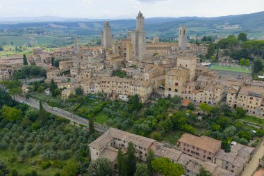 Aerial view of San Gimignanos medieval stone towers, city walls, and surrounding Tuscan countryside, a UNESCO-listed trading center.