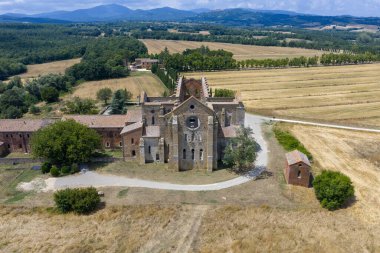 Chiesa dei Santi Giusto ve Clemente 'nin Volterra çatılarından yükselişi, Toskana tepeleriyle çevrili yumuşak akşam sisi.