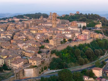Toskana 'daki Volterra Tepesi' nin havadan görünüşü, ortaçağ taş duvarları, terasotta çatıları, kilise kuleleri ve alacakaranlıktaki kırsal bölgeleri gösteriyor..