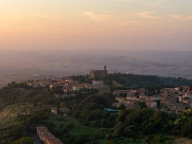 Gün batımında Volterra tepesi ve kırsal bölge manzarası, Chiesa dei Santi Giusto ve Clemente ortaçağ çatılarından yükseliyor..