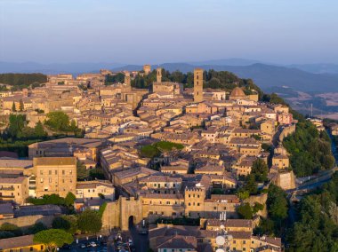 Günbatımında Volterra Tepesi 'nin tarihi merkezinin havadan görünüşü ortaçağ taş evleri, kuleler, duvarlar ve Toskana tepelerini gösteriyor..