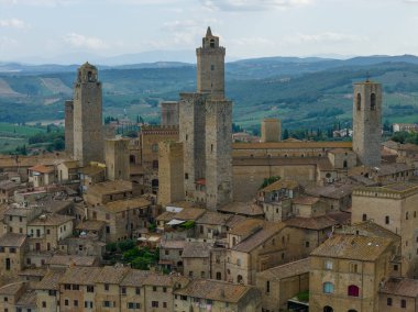 İtalya 'nın orta kesimindeki San Gimignanos ortaçağ taş kulelerinin çatıları ve Toskana kırsalları üzerinde yükselen hava manzarası.