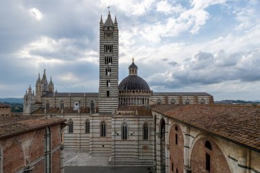 Gotik Siena Katedrali çizgili mermer ve çarpıcı bir kubbeye sahiptir. 13. yüzyılda inşa edilen yapı İtalyan Gotik mimarisini simgeliyor. Bulutlu gökyüzü Siena, İtalya 'ya dram katıyor.