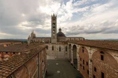 Çizgili mermer cepheli Gotik Siena Katedrali, Piazza del Duomo 'ya bakıyor. 1263 yılında tamamlandığında, dramatik bulutlu gökyüzünün altında karmaşık mozaikler, yükselen campanile ve ikonik kubbe yer alır..
