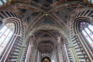 Siena, İtalya - 19 Temmuz 2025: Siena Katedrali 'nin Gotik iç mimarisi, çizgili mermer sütunlar, yıldız motifleri ve vitray pencerelerle süslenmiş kubbeli tavanlar göstermektedir..