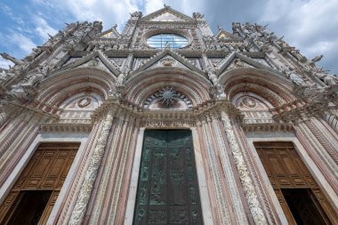 Siena Katedrali beyaz, yeşil ve kırmızı renklerden oluşan karmaşık mermer cepheli Gotik mimariye sahiptir. İtalya, Siena 'daki zengin detaylı oymaları ve tarihsel önemi ile bilinir..