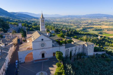 İtalya 'nın Assisi kentindeki 13. yüzyıl Bazilikası di Santa Chiara' da pembe ve beyaz taş şeritler, büyük bir gül penceresi ve Romanesk mimari sergilenmektedir. Sabah ışığı dingin görünüşünü arttırır..