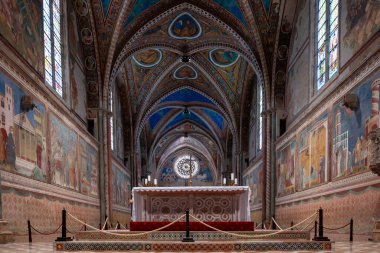 Assisi, İtalya - 17 Temmuz 2025: Bazilikanın Gotik iç mekanında Giotto 'nun canlı freskleri yer almaktadır. Karmaşık mermer döşeme ve boyalı cam Assisi, İtalya 'daki kutsal alanı aydınlatıyor.