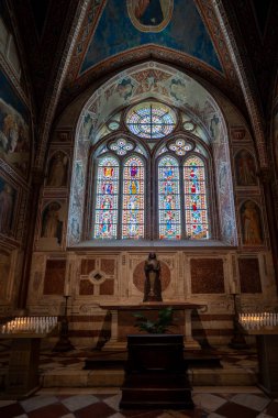 Assisi, İtalya - 17 Temmuz 2025: Assisi 'deki Papalık Bazilikası' nın içinde Gotik cam pencereler, ortaçağ freskleri ve sönük mum ışığında bir atmosfer yer alıyor. St 'e bağlı önemli bir site.