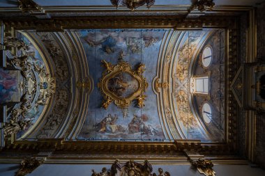 Assisi, İtalya - 17 Temmuz 2025: Santa Maria sopra Minerva 'nın karmaşık Barok tavanı, Assisi, İtalya, süslemeli freskler ve dairesel pencerelerden gelen yumuşak doğal ışık altında altın aksanlar.
