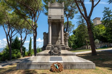 İtalya 'nın Spoleto kentindeki gri taştan yapılan savaş anıtı yüksek çam ağaçları arasında yer alıyor..
