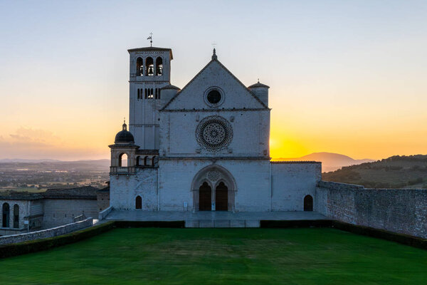 The Papal Basilica of Saint Francis, a masterpiece of Romanesque architecture, silhouetted at sunset in Assisi, Italy. Known for Giotto's frescoes, it embodies Franciscan spirituality and history.