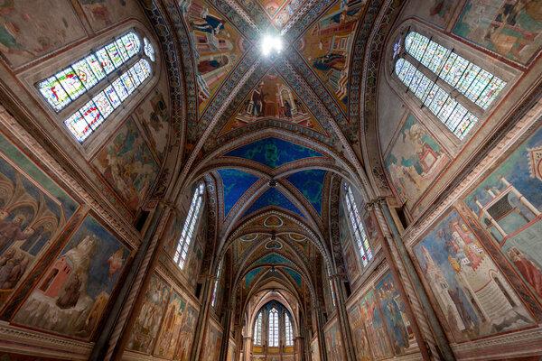 Assisi, Italy - Jul 17, 2025: The Papal Basilica of Saint Francis in Assisi features 13th-century frescoes depicting biblical scenes. The Gothic vaults are adorned with vibrant blue and warm earth