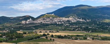 İtalya 'nın Assisi kentindeki Saint Francis Bazilikası' nın havadan görünüşü Gotik mimariyi Subasio Dağı 'na karşı sergiliyor. Umbrian sahalarının koyu tonları yeşil yamaçlarla tezat oluşturuyor..