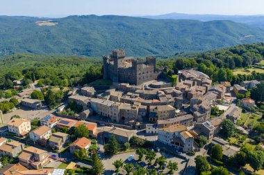 Torre Alfina, İtalya 'daki Torre Alfina Kalesi yukarıdan ele geçirildi. Ortaçağ kalesinde, güneşli bir yaz gününde yemyeşil ve köy evleri arasında kahverengi taş mimari sergileniyor..