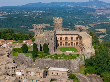 Torre Alfina, İtalya 'daki Torre Alfina Kalesi yukarıdan ele geçirildi. Ortaçağ kalesinde, güneşli bir yaz gününde yemyeşil ve köy evleri arasında kahverengi taş mimari sergileniyor..