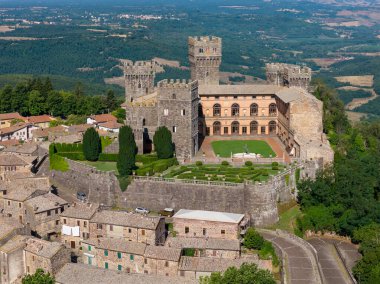 Torre Alfina, İtalya 'daki Torre Alfina Kalesi yukarıdan ele geçirildi. Ortaçağ kalesinde, güneşli bir yaz gününde yemyeşil ve köy evleri arasında kahverengi taş mimari sergileniyor..