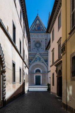 İtalya 'daki Gotik bir başyapıt olan Orvieto Katedrali, karmaşık mozaikleri ve heykelleri olan çarpıcı bir polikrom perisine ev sahipliği yapıyor. Dar sokaklar tarafından çerçevelenmiş güneş ışığı cephesi ortaçağ ihtişamını vurguluyor. 