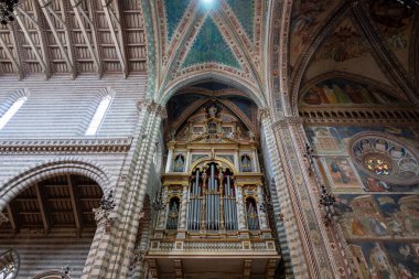 Orvieto, İtalya - 14 Temmuz 2025: Gotik polikrom mermer çizgili Orvieto Katedrali 'nin iç mimarisi, freskler ve yüksek tavan altında bir Rönesans organı.