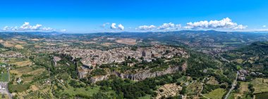 Orvieto, İtalya 'nın havadan görünüşü, tarihi ortaçağ mimarisini volkanik uçurumların tepesinde sergiliyor. Canlı manzara ve berrak yaz gökyüzü Etrüsk 'ten etkilenen şehir manzarasını geliştirir..