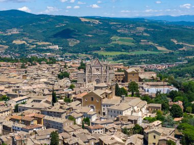 1290 'dan inşa edilen Gotik Orvieto Katedrali, çizgili mermer cephesi ve gül penceresiyle kasabaya hükmediyor. Hava görüntüsü karmaşık şehir planlarını, terracotta çatılarını, bereketli Umbrian manzarasını gözler önüne seriyor..